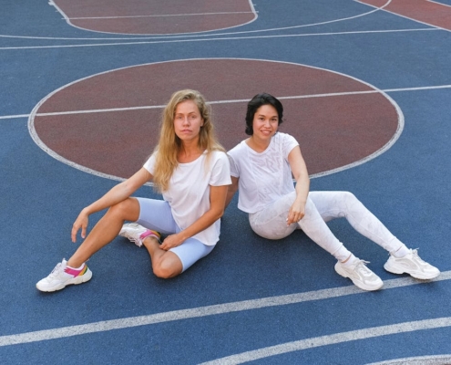 Dos mujeres sentadas en pista de baloncesto antes de hacer deporte